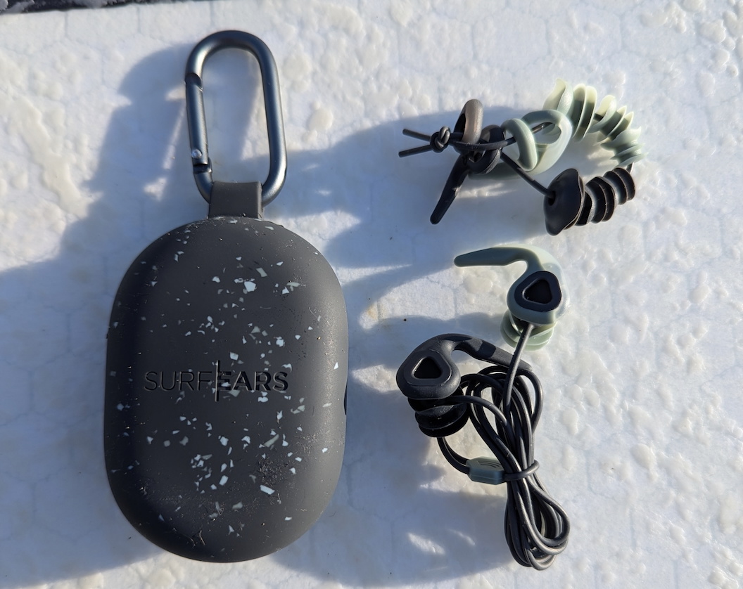 SurfEars earplugs, spare tips and leash laid out beside their speckled grey carry case